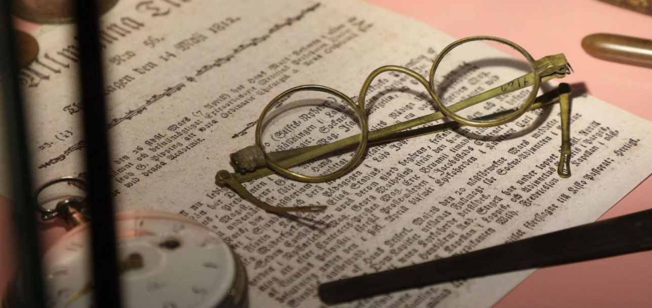 Lähikuva Apteekkimuseon näyttelyvitriinistä: vanhat silmälasit sekä käsinkirjoitettu paperiarkki