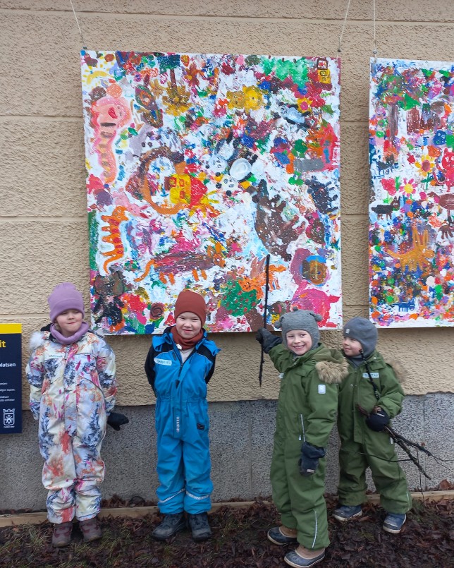 Lapset värikkäiden maalausten edessä.