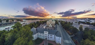 Ilmakuva, jossa keskellä Turun linna ja ympärillä rakennuksia, Aurajoen suu ja satama-aluetta.