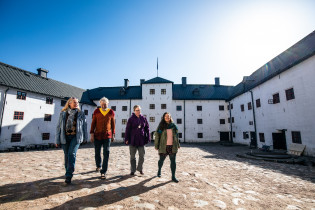 Neljä ihmistä kävelee Turun linnan sisäpihalla.