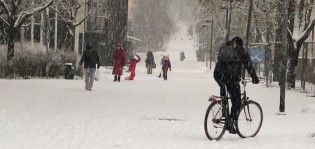 Runosmäen Piiparinpolulla lumisateessa pyöräilija ja perheitä ulkoilemassa.