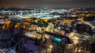 Linnanniemen alue ja Turun linnan seinään heijastettu valoteos pimeässä illassa otetussa ilmakuvassa.