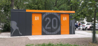 Kupittaanpuiston uusi yleisö-wc, harmaat liikennepuistoaihein kuvioidut seinät kirkkaan oransseilla ovilla ja kattolipalla