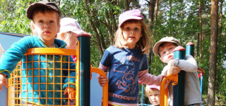 Kolme tyttöä ja kaksi poikaa lippikset päässä leikkipuistossa
