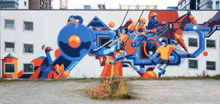 Sinistä ja oranssia yhdistelevä moniulotteinen seinämaalaus kuvaa Kupittaanpuiston historiaa.
