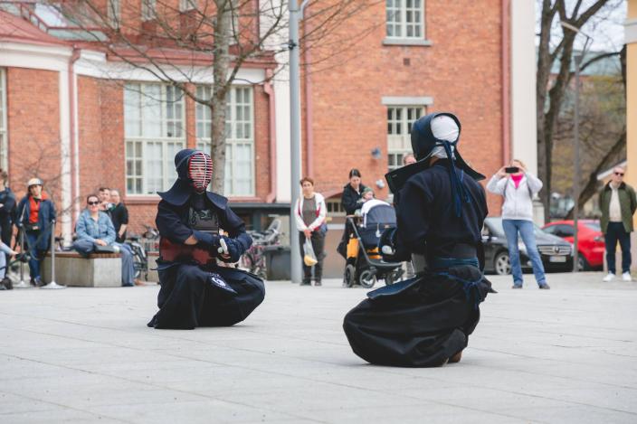 Kaksi mustiin pukeutunutta kamppailulajin harrastajaa kirjaston pihalla.  (Kuva: Akinori Ikeda)