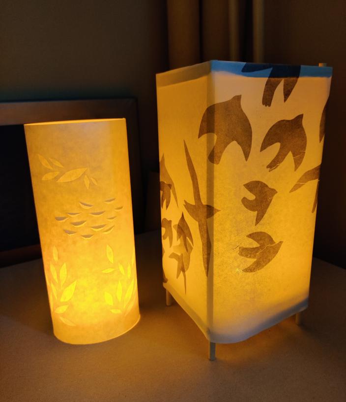 Kuvassa on kaksi lyhtyä, joissa on kynttilät sisällä. Toisessa lyhdyssä on lintujen kuvia. (Kuva: Tuuli Sunden-Uusimäki)