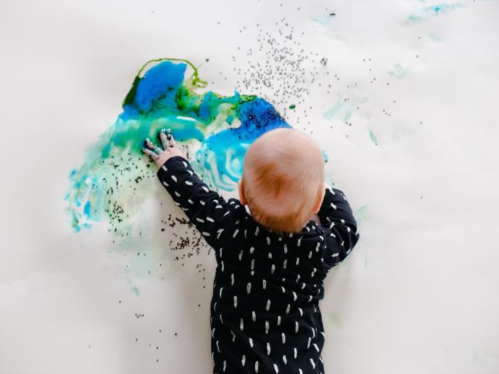 Vauva maalaamassa värejä isolle paperille. (Kuva: Denisse Islas Ferreira)