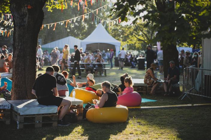 Photo from the Summer Peace Festival 2021, people sitting in the festival area in the sunshine.