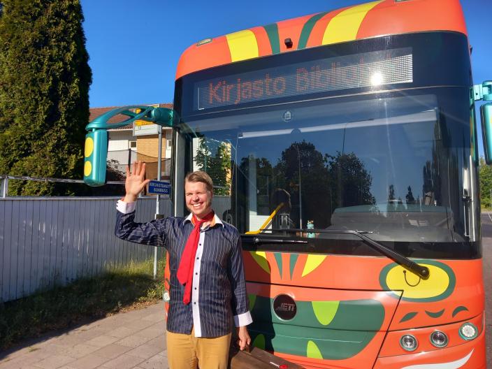 Sirkusesiintyjä heiluttaa kirjastoauton edessä. (Kuva: Heli Koskinen)