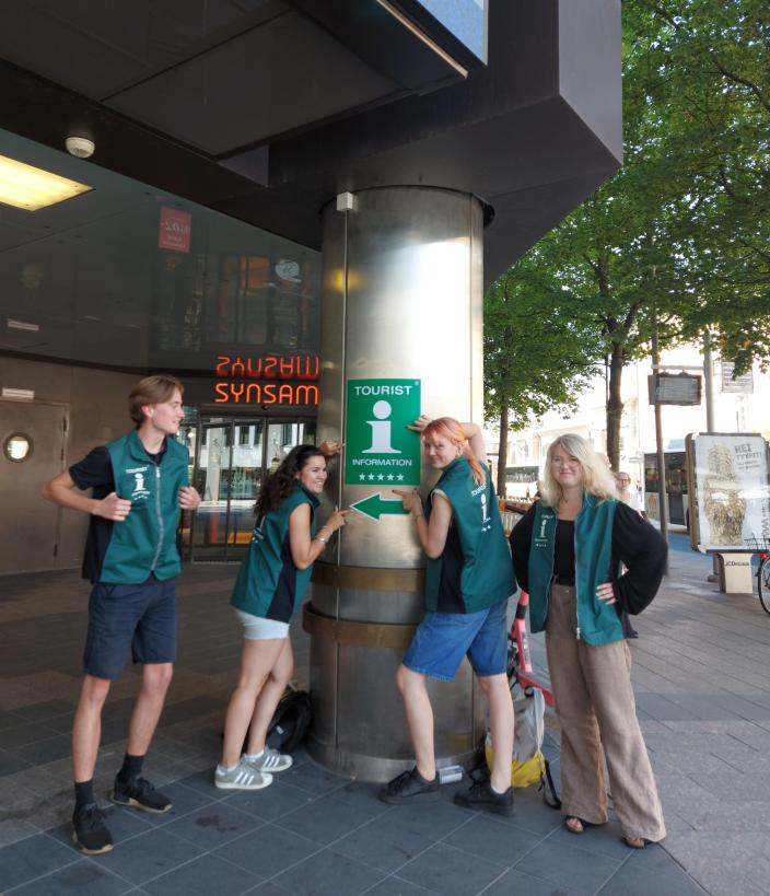 Neljä vihreisiin liiveihin pukeutunutta nuorta seisoo matkailuneuvonnan edessä. (Kuva: Hilda Autero)