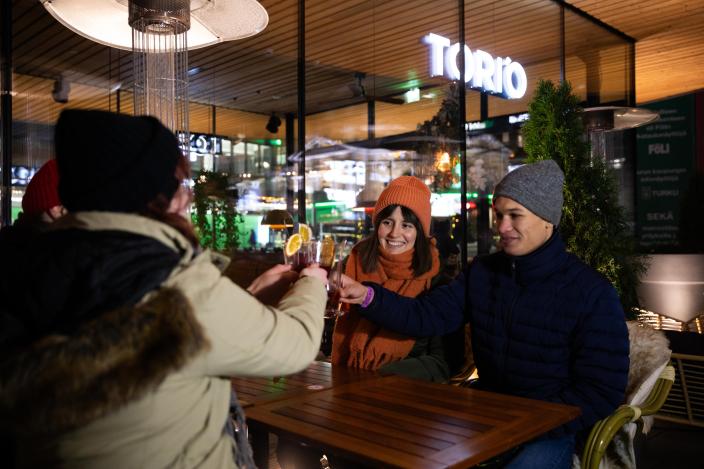 Nuoret aikuiset istuvat talvella ravintolan ulkoterassilla ja skoolaavat juomalaseilla. (Picture: Visit Turku Archipelago)