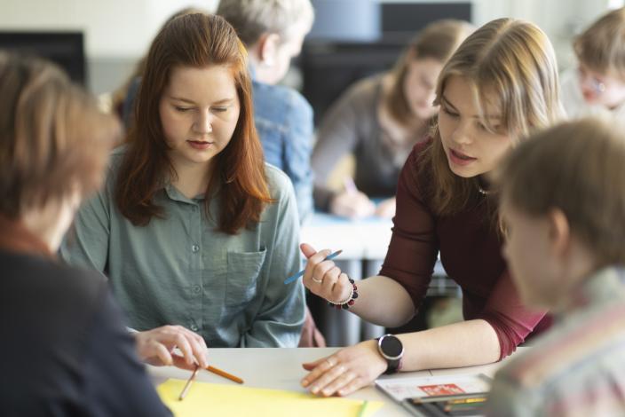 Upper secondary school students are working on a group project in a classroom. In the foreground, there is a table with paper and pens on it. (Picture: Jussi Vierimaa)