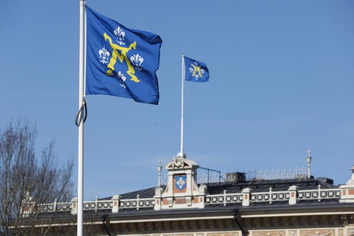 Kaksi Turun vaakunalippua liehumassa Turun kaupungintalon katolla sinistä taivasta vasten. (Kuva: Pasi Leino)