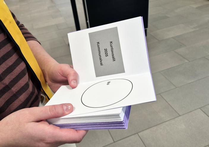 Vaalitoimitsijan kädet, joissa on nippu vaalilipukkeita. (Kuva: Helena Erkkilä)