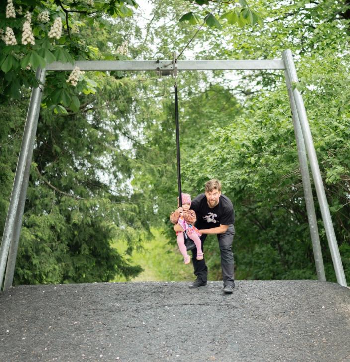 Isä nostaa lapsen vaijeriliukuun Seikkailupuistossa. (Kuva: Hannu Aaltonen)
