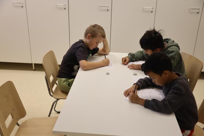 På bilden utför elever i årskurs två en uppgift från känslokompetensverkstaden vid ett bord. (Foto: Vilhelmiina Vesanen)