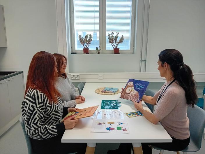 Aluesosionomi esittelee kuvatukia kahdelle asiakkaalle pöydän ääressä. (Kuva: Jatta Kalasniemi)