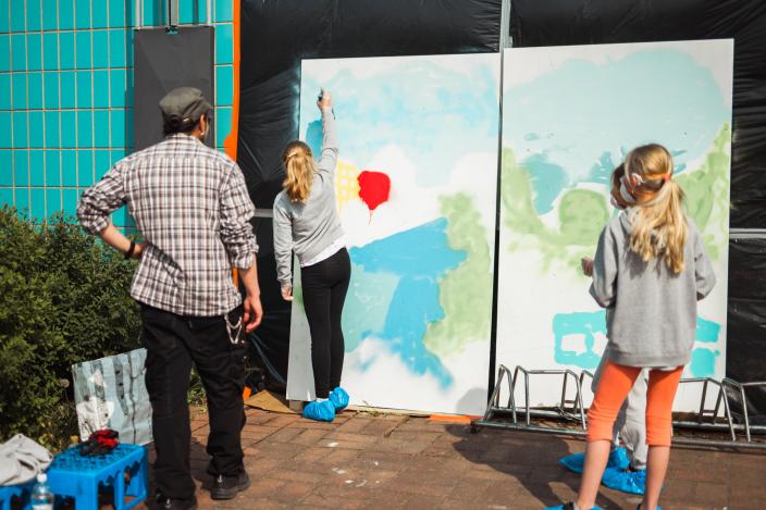 Taiteilija seuraa, kun 2 nuorta maalaa graffititeosta. (Kuva: Jussi Virkkumaa)