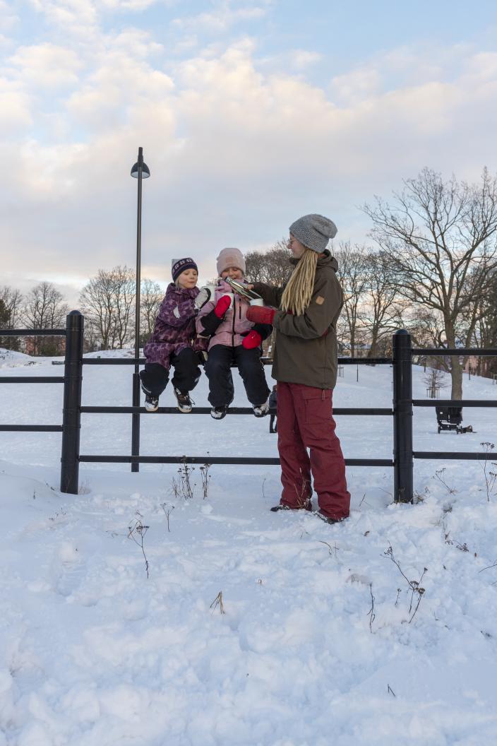 En mamma häller upp en varm dryck från en termos för två barn i Puolalanpuisto. (Foto: Timo Jakonen)