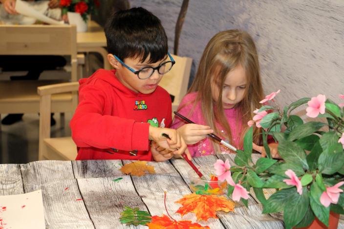 Två barn målar höstlöv. (Foto: Hannele Sivonen)