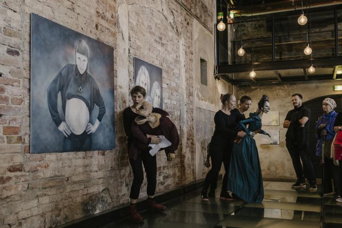 Nukketeatteritaiteilijat nukkejen kanssa, tiiliseinällä kuvataidetta. (Kuva: Rosa Huuska)