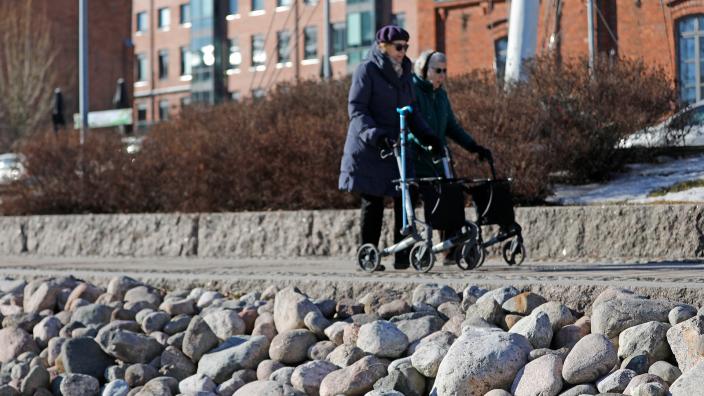 Kaksi ikäihmistä kävelee rollaattoreilla talvisessa Aurajokimaisemassa. (Kuva: Pasi Leino)