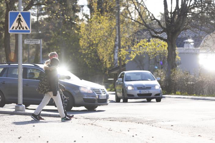 Aikuinen ja lapsi ylittämässä suojatietä, kaksi autoa on pysähtynyt odottamaan kulkijoiden ylitystä. (Kuva: Suvi Elo)