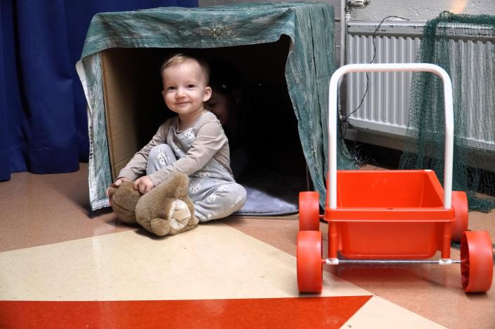 Ett litet barn sitter på golvet och leker med en teddybjörn. (Foto: Hannele Sivonen)