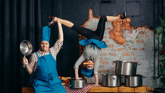 kaksi kokiksi pukeutunutta sirkustaiteilijaa temppuilee keittiössä kattiloiden keskellä (Kuva: Kai Kuusisto)