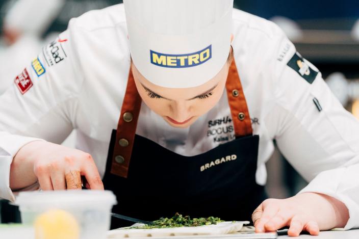 Kokki asettelee ruokaa lautaselle pinseteillä.