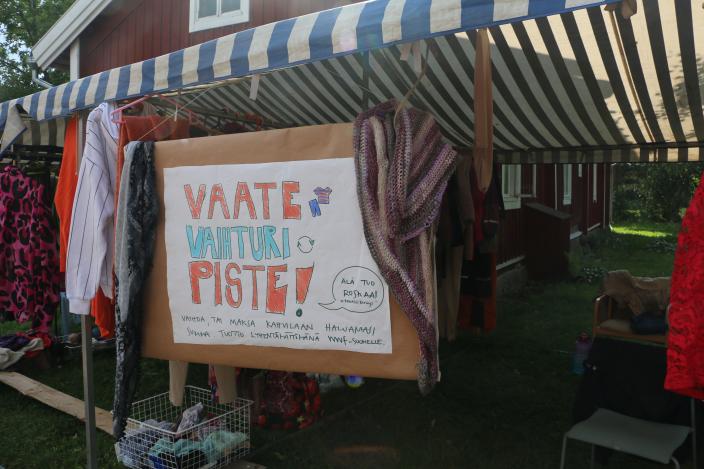 Vaatteiden vaihtopiste Koroisissa, jossa katoksen alla ulkona on vaatteita ripustettuna. (Kuva: Petra Karjalainen)