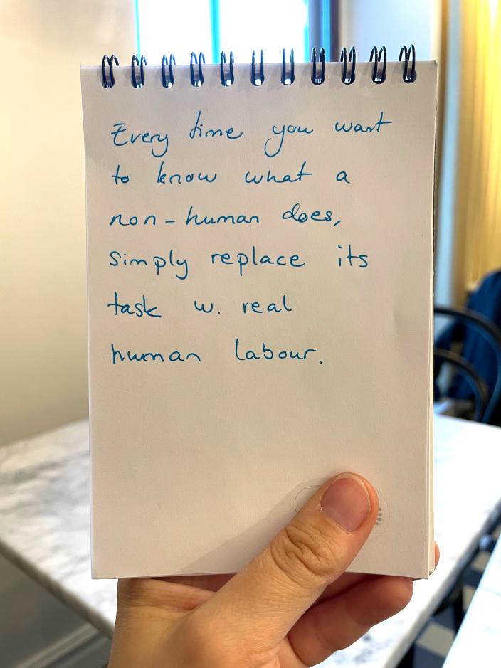 Lappu, jossa lukee: Everytime you want to know what a non-human does, simply replace its task with real human labour. (Foto: Sandrina Lindgren)