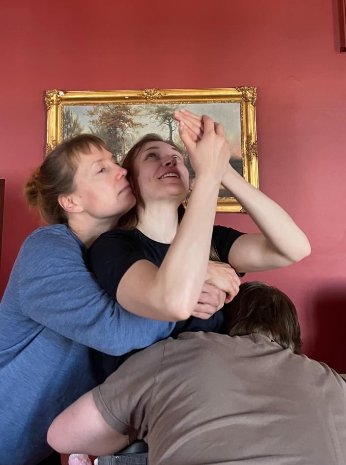 Lähikuva kahdesta tanssijasta halaamassa Elohuone-näytelmän ihmishahmoa. (Foto: Sandrina Lindgren)