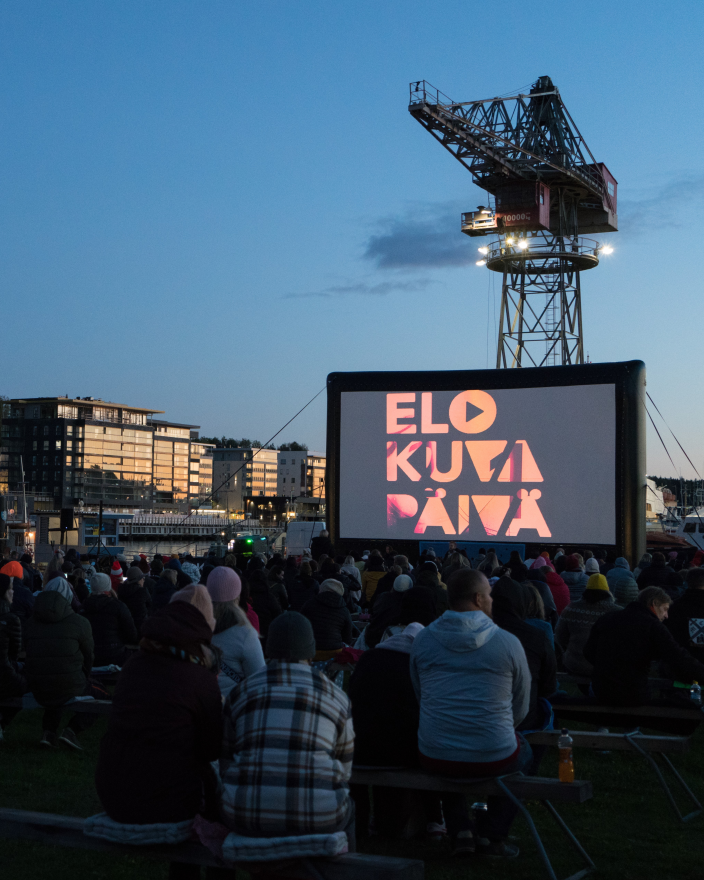 Yleisö seuraamassa elokuvaa jokirannassa. (Kuva: Ella Metsälä)