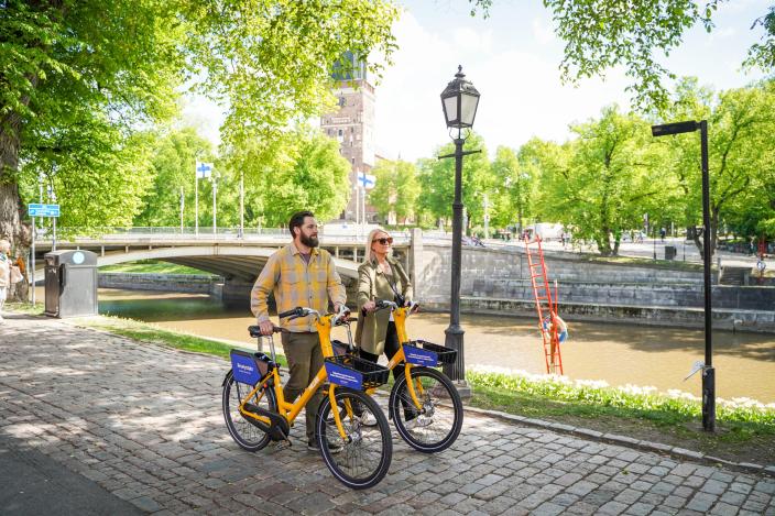 A man and woman leading their Fölläri bikes along the Aura River. (Picture: Åbo Creatives / Visit Turku Archipelago)