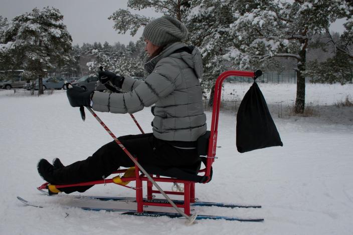 A woman sits on a sled and pushes with ski poles. (Picture: Johanna Friman)