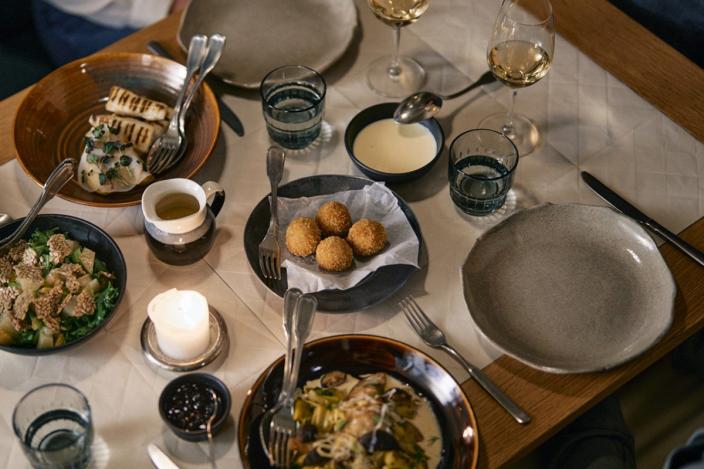 Kattaus kahdelle kynttilänvalossa, tarjolla erilaisia kasviherkkuja ja valkoviiniä. 