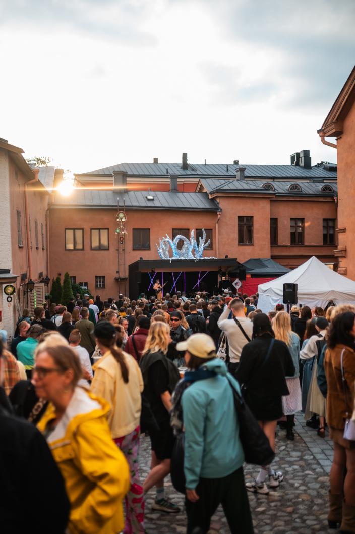 Yleisöä festivaalilavan edustalla, ympärillä vanhoja rakennuksia (Kuva: Milla Ilkamo)
