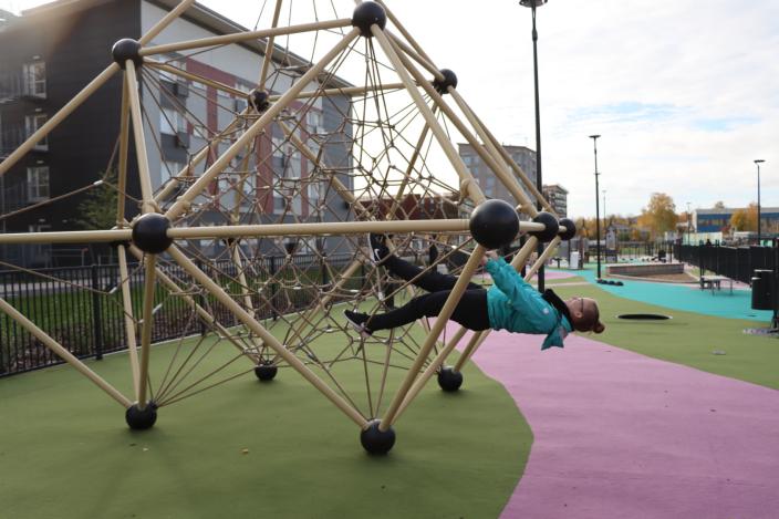 Nainen roikkuu Kirstinpuiston leikkikentän kiipeilytelineessä.  (Kuva: Anna-Kaisa Kaukola)