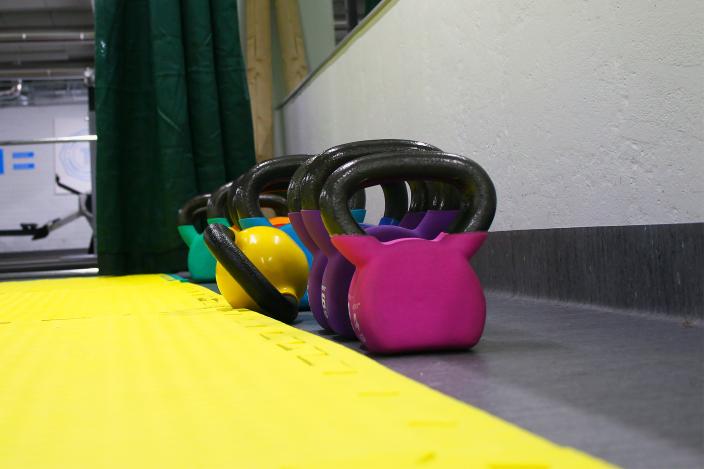 Färggranna kettlebells står bredvid varandra på golvet i gymnastiksalen. (Foto: Pekka Mentunen)