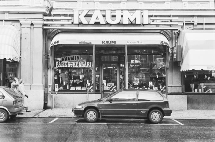 Vaatetusliikkeen myynti-ikkuna, jonka päällä markiisi ja yläpuolella valomainos tekstillä Kaumi. (Kuva: Martti Puhakka, Turun kaupunginmuseo)