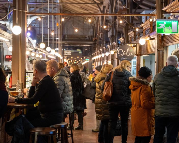 Talvivaatteisiin pukeutuneita ihmisiä Turun Kauppahallissa. (Kuva: Abo Creatives)