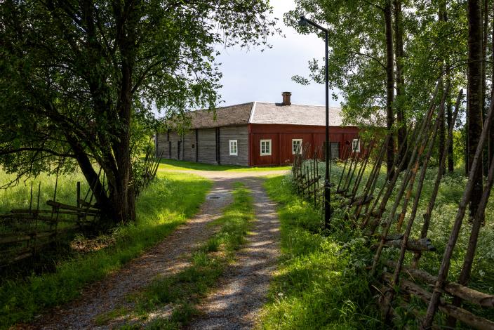 Vanha, suurikokoinen talonpoikaisrakennus keskellä vehreää maisemaa. (Kuva: Jari Laurén)