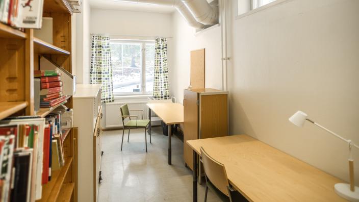 Pieni työhuone, jossa pöytiä, tuoleja ja kirjahylly. (Kuva: Jussi Virkkumaa)