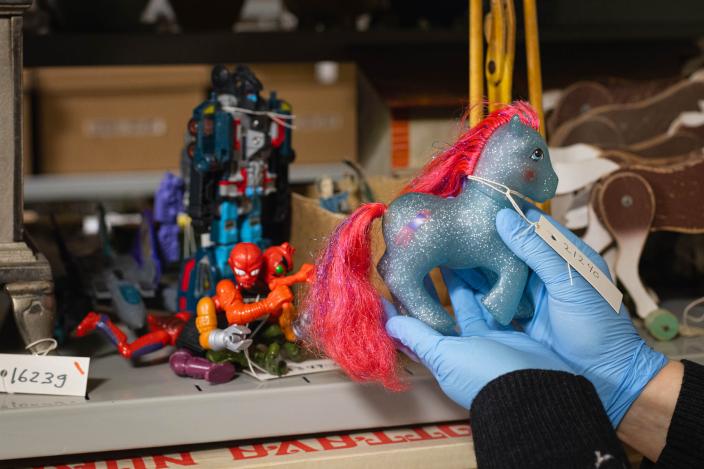 Leluja museon kokoelmavarastossa, tutkijan pitää My Little Pony -nukkea kädessä. (Kuva: Ville Mäkilä)