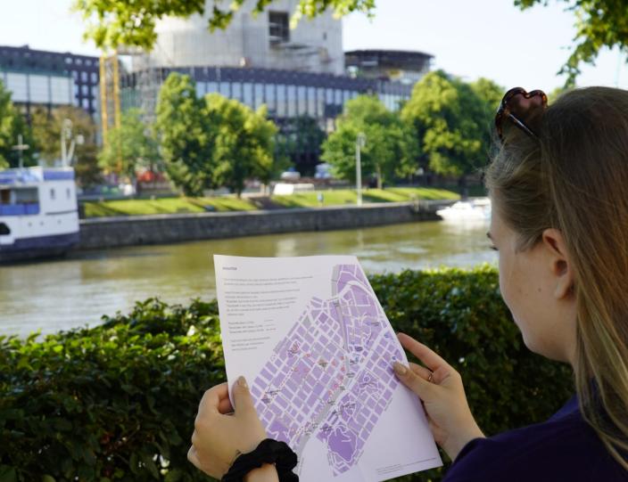 Henkilö katselee kulttuurikuntoilukarttaa Aurajokirannassa. (Kuva: Lotta Viitala)