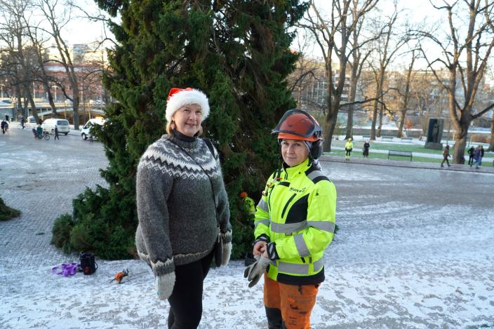 Elina Maisila, ordförande för Tarvaisten Seudun Kylät rf som har donerat julgranen till Domkyrkan, och Kuntecs arbetsplatschef Jaana Saraste ler framför julgranen. (Foto: Vilhelmina Vesanen)