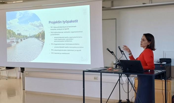 Julia Chir esittelemässä valkokankaalta Kulttuurin jokirannan yhteistyöverkosto -projektin työpaketteja. (Kuva: Heli Lempa)