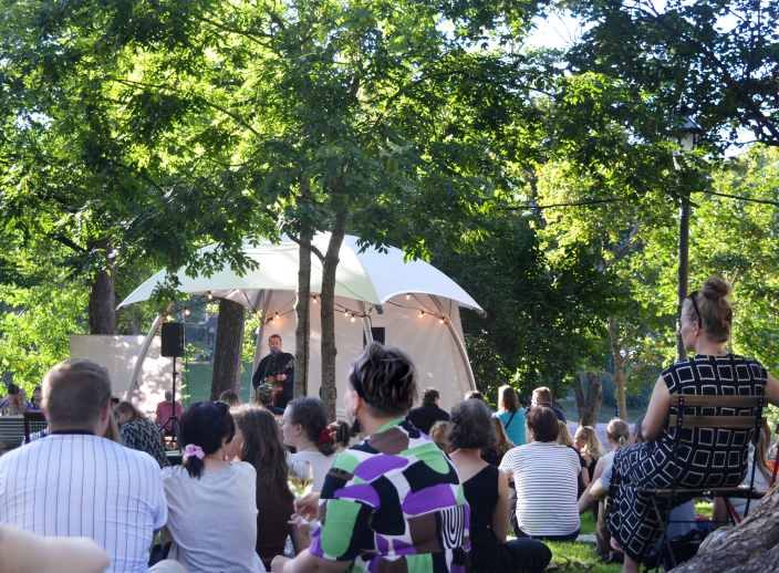 Ihmisiä puistossa kuuntelemassa telttalavalla esiintyvää muusikkoa. (Kuva: Anne-Mari Savola)